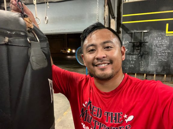 Ace smiling next to a heavy bag in a boxing gym